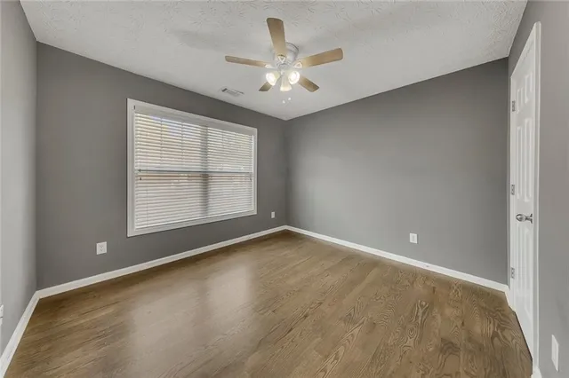 an empty room with chandelier fan and windows