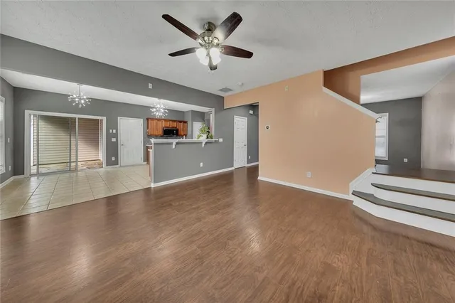 a view of an empty room with wooden floor and a ceiling fan