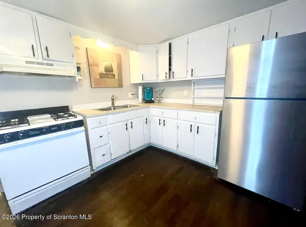 a kitchen with a sink a refrigerator and white cabinets