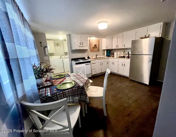 a kitchen with stainless steel appliances a refrigerator a sink a stove a dining table and chairs