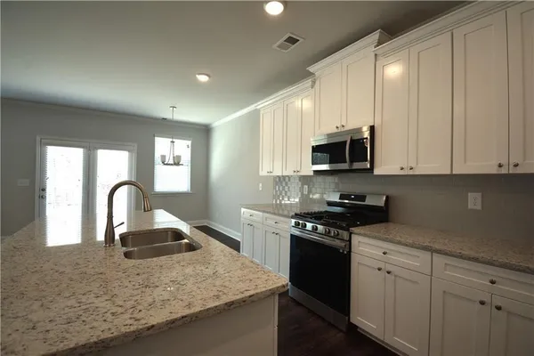 a kitchen with granite countertop a stove top oven microwave and cabinets