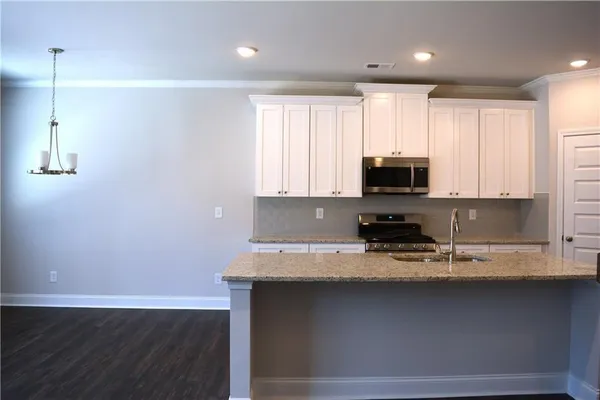 a kitchen with stainless steel appliances granite countertop a sink a stove a microwave and wooden cabinets