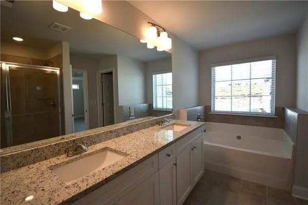 a bathroom with a granite countertop tub a double vanity sink and mirror