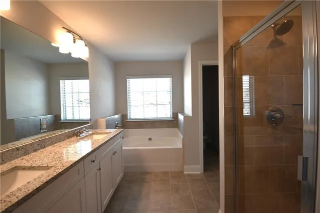 a bathroom with a granite countertop tub sink and mirror
