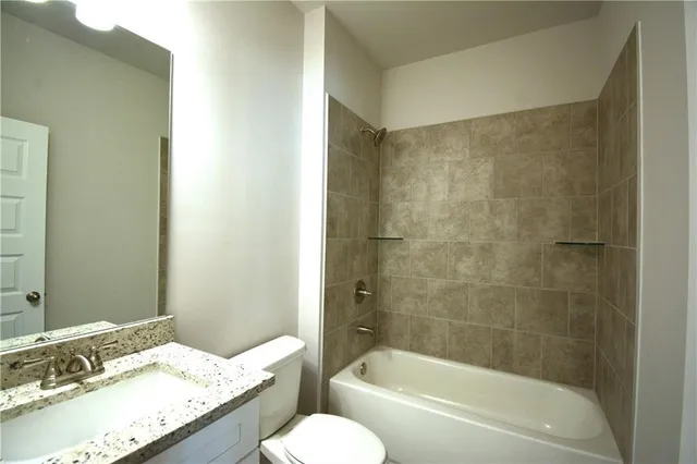 a bathroom with a granite countertop sink mirror toilet and bathtub