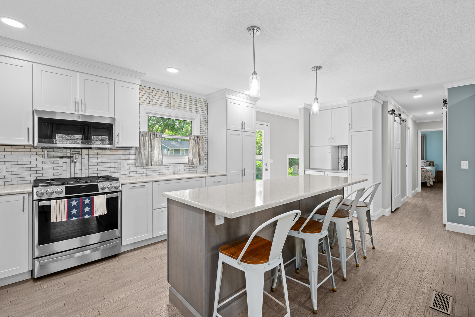 506 Bush Street Reynolds, IL 61279 - Photo 10 of 37 a kitchen with stainless steel appliances kitchen island granite countertop a stove a sink a microwave a refrigerator and white cabinets with wooden floor
