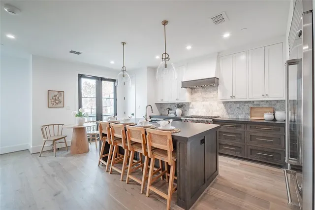 a kitchen with a stove a sink a kitchen island with chairs and wooden floor