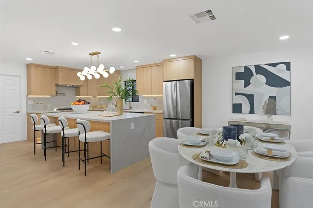 a kitchen with a dining table chairs and refrigerator