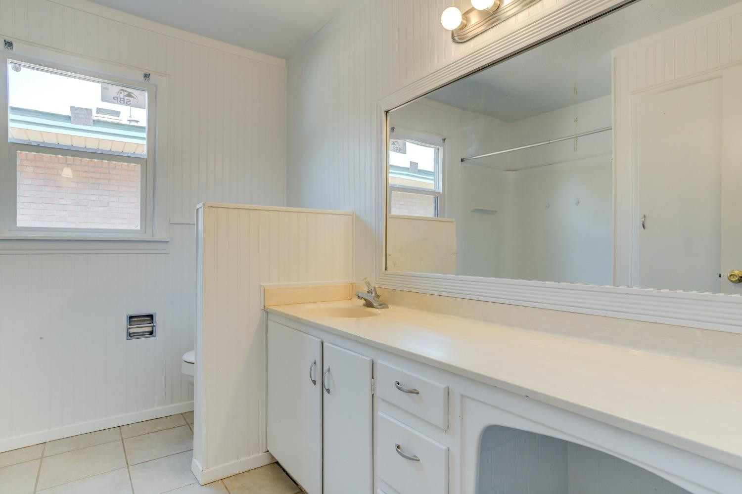3411 41st Street Lubbock, TX 79413 - Photo 22 of 29 a bathroom with a sink and a mirror