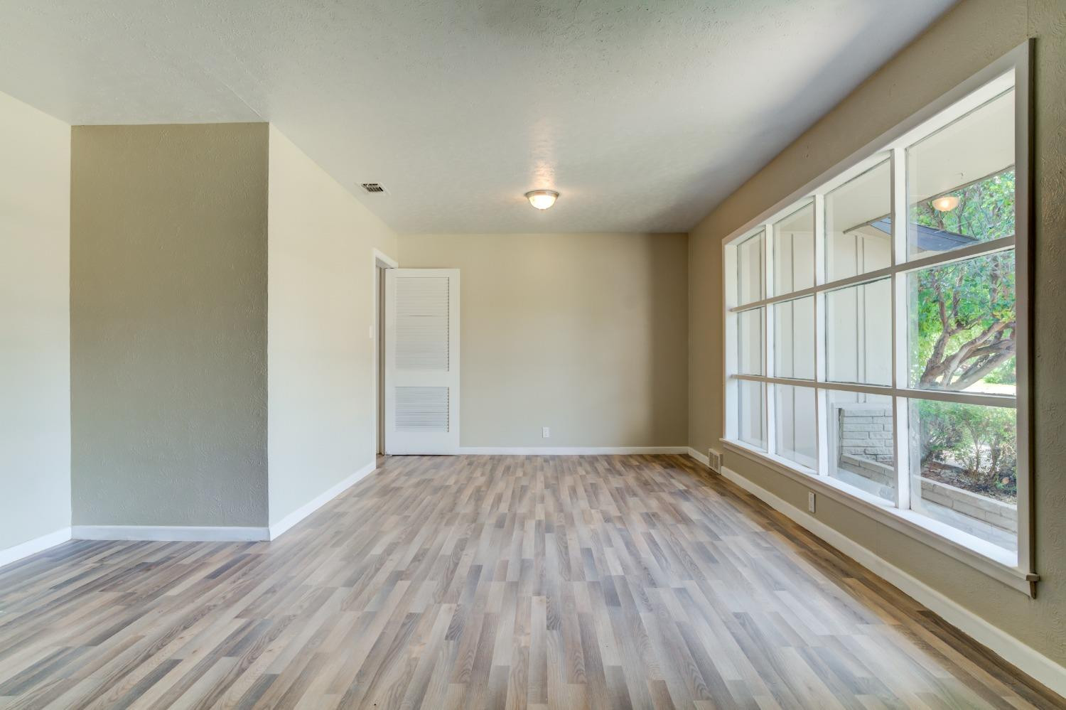 3411 41st Street Lubbock, TX 79413 - Photo 4 of 29 a view of an empty room with wooden floor and a window