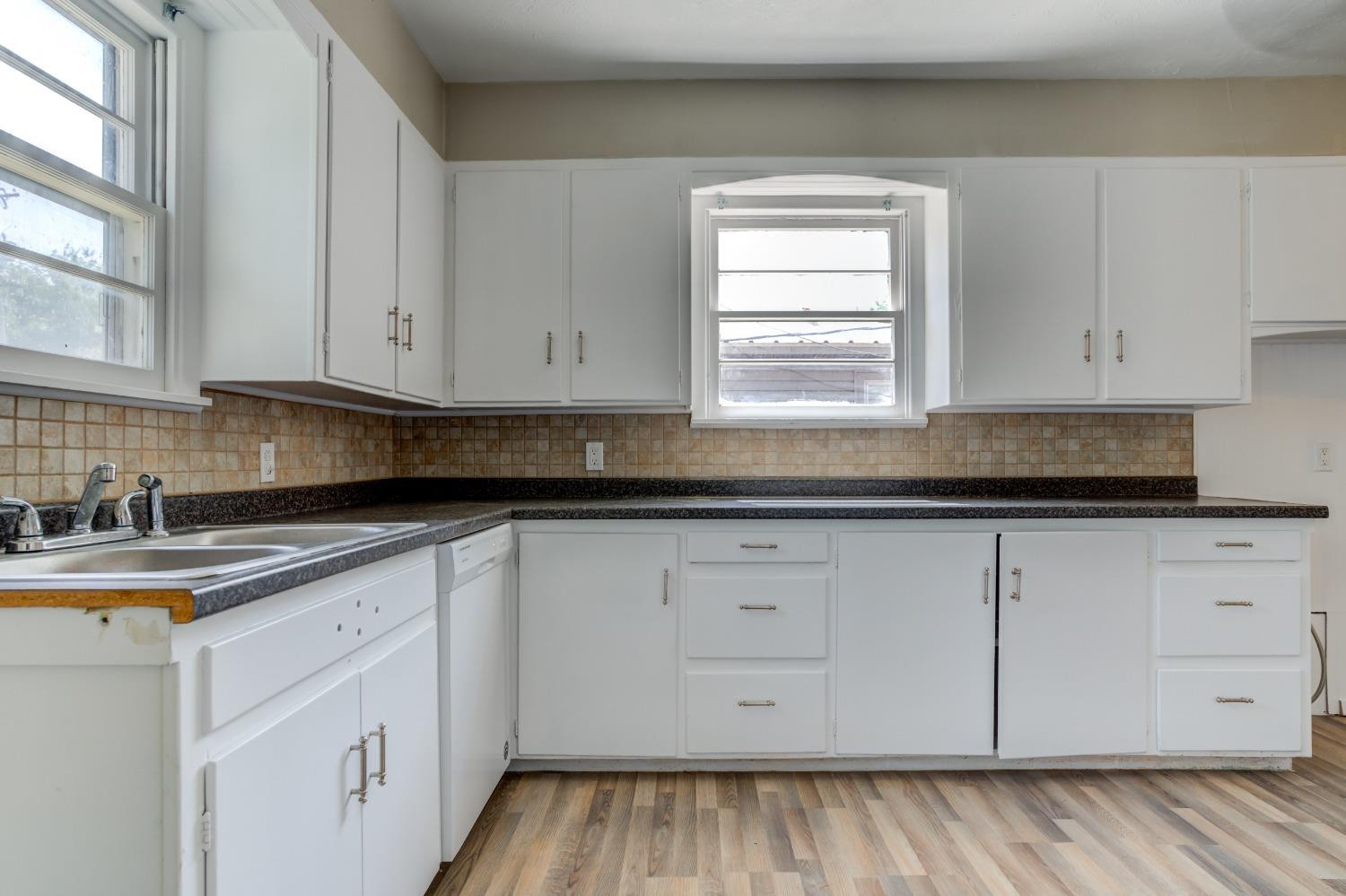 3411 41st Street Lubbock, TX 79413 - Photo 10 of 29 a kitchen with granite countertop white cabinets and white appliances