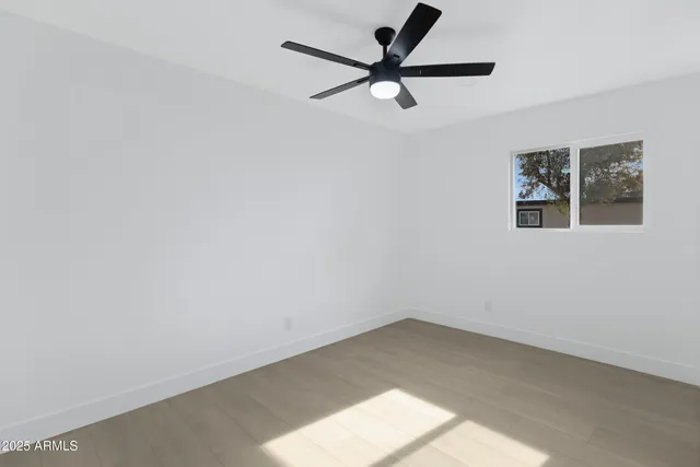an empty room with a window and a ceiling fan