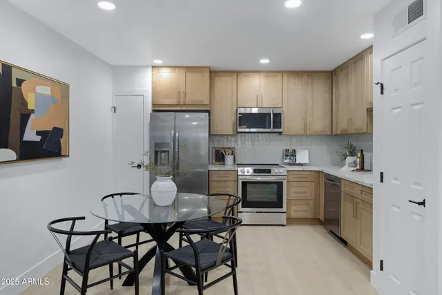 a kitchen with stainless steel appliances kitchen island granite countertop a kitchen island a stove a table and chairs