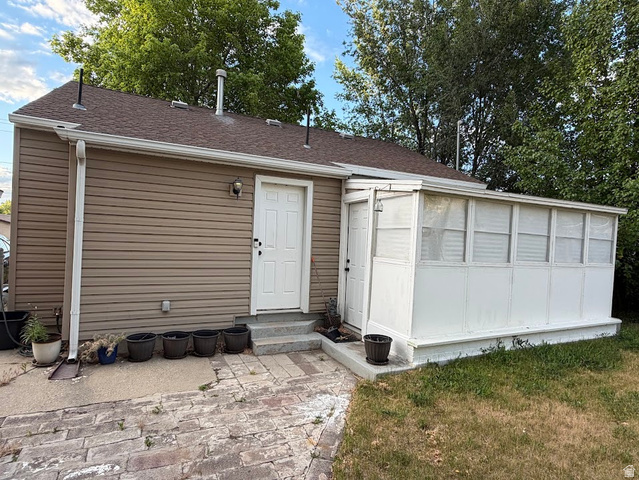 737 Wasatch Street Midvale, UT 84047 - Photo 22 of 29 Rear exterior featuring a sunroom addition with multiple windows, tan siding, and a shingled roof