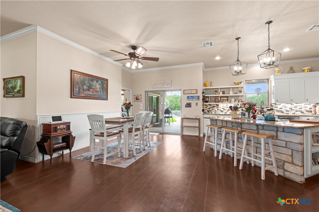 2649 Bowles Ranch Road Belton, TX 76513 - Photo 6 of 36 a view of a dining room and livingroom with furniture wooden floor a rug a flat screen tv a painting and a chandelier
