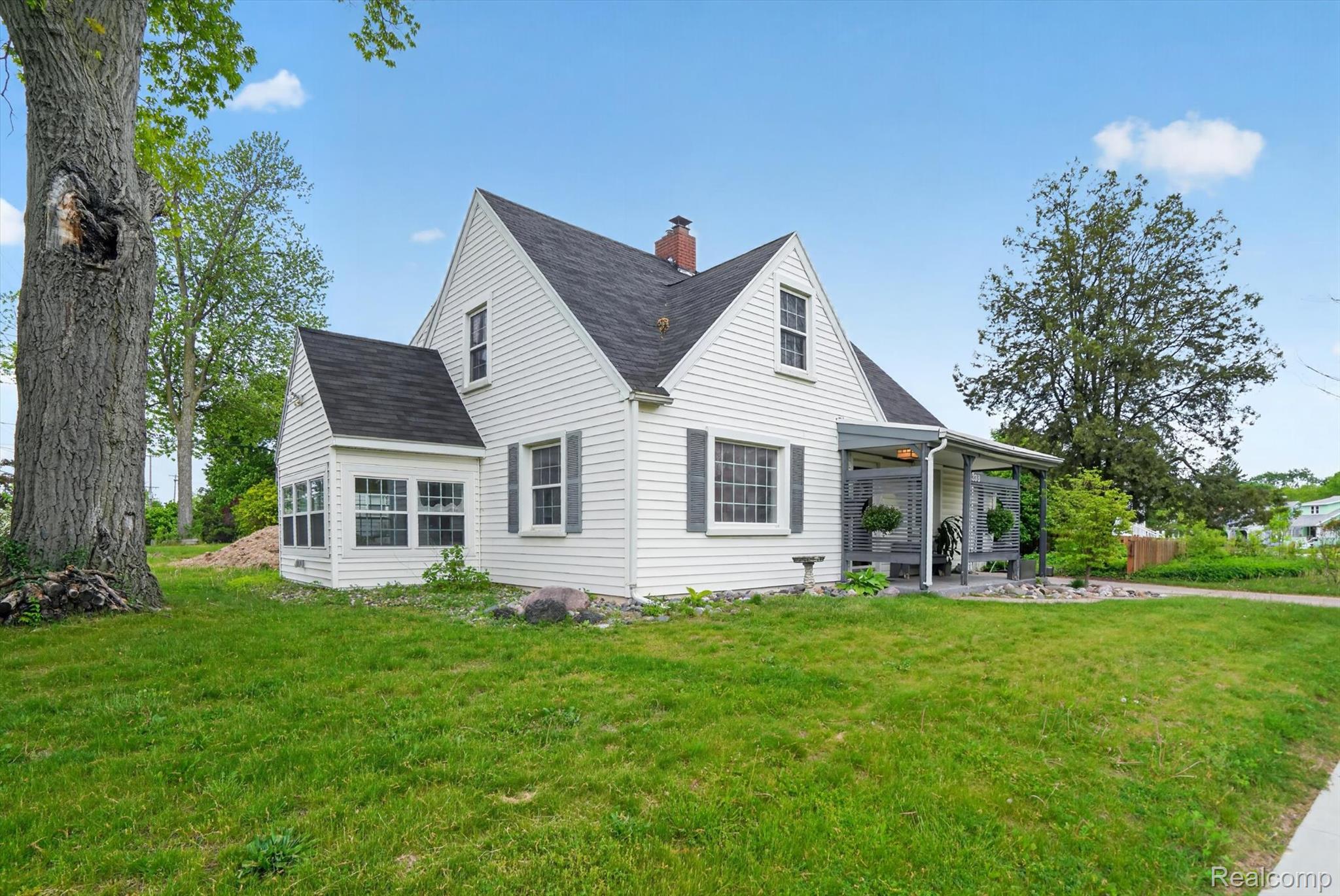 338 Kensington Road Lansing, MI 48910 - Photo 2 of 35 View of property exterior featuring a yard, a shingled roof, and a chimney