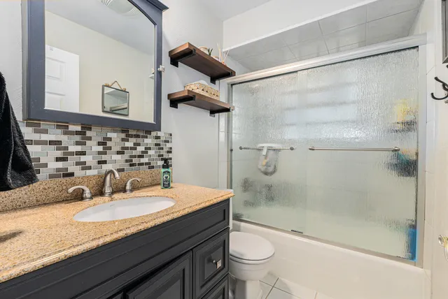 a bathroom with a granite countertop sink a toilet and shower