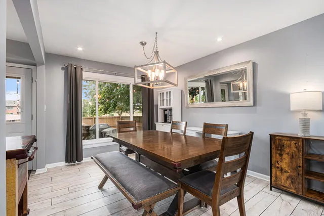 a dining room with wooden floor a chandelier a wooden table and chairs
