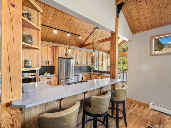 a kitchen with stainless steel appliances kitchen island granite countertop a table chairs in it and wooden floors