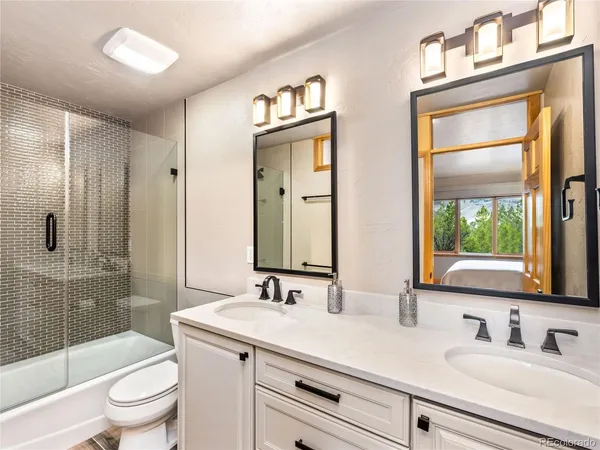a bathroom with double vanity sink toilet and shower