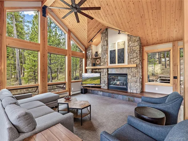 a living room with furniture a fireplace and large windows