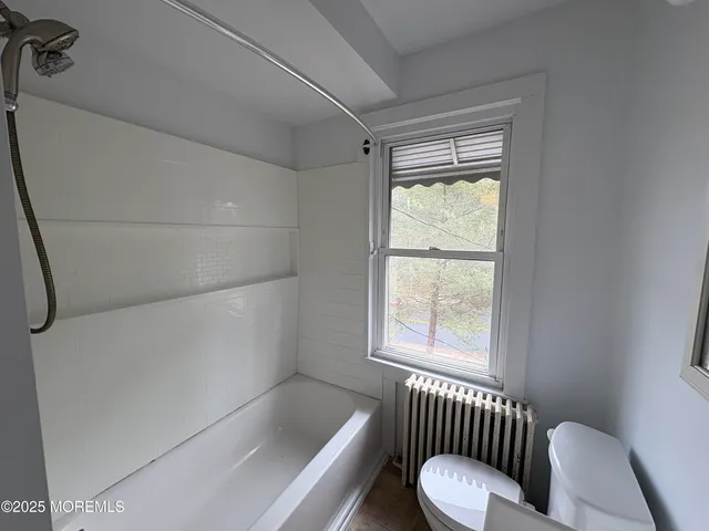a bathroom with a tub toilet and window
