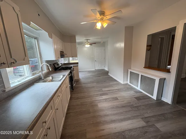 a kitchen with stainless steel appliances granite countertop a sink a stove top oven a chimney and a refrigerator