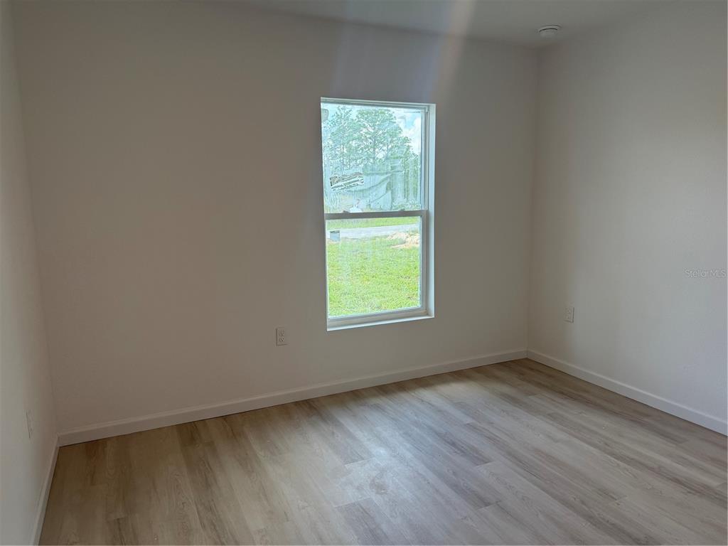 12847 Southwest 84th Terrace Road Ocala, FL 34473 - Photo 11 of 16 an empty room with wooden floor and windows