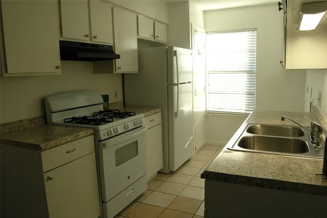 a kitchen with granite countertop a sink stove and refrigerator