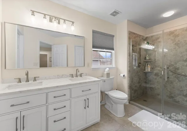 a bathroom with a double vanity sink toilet mirror and shower
