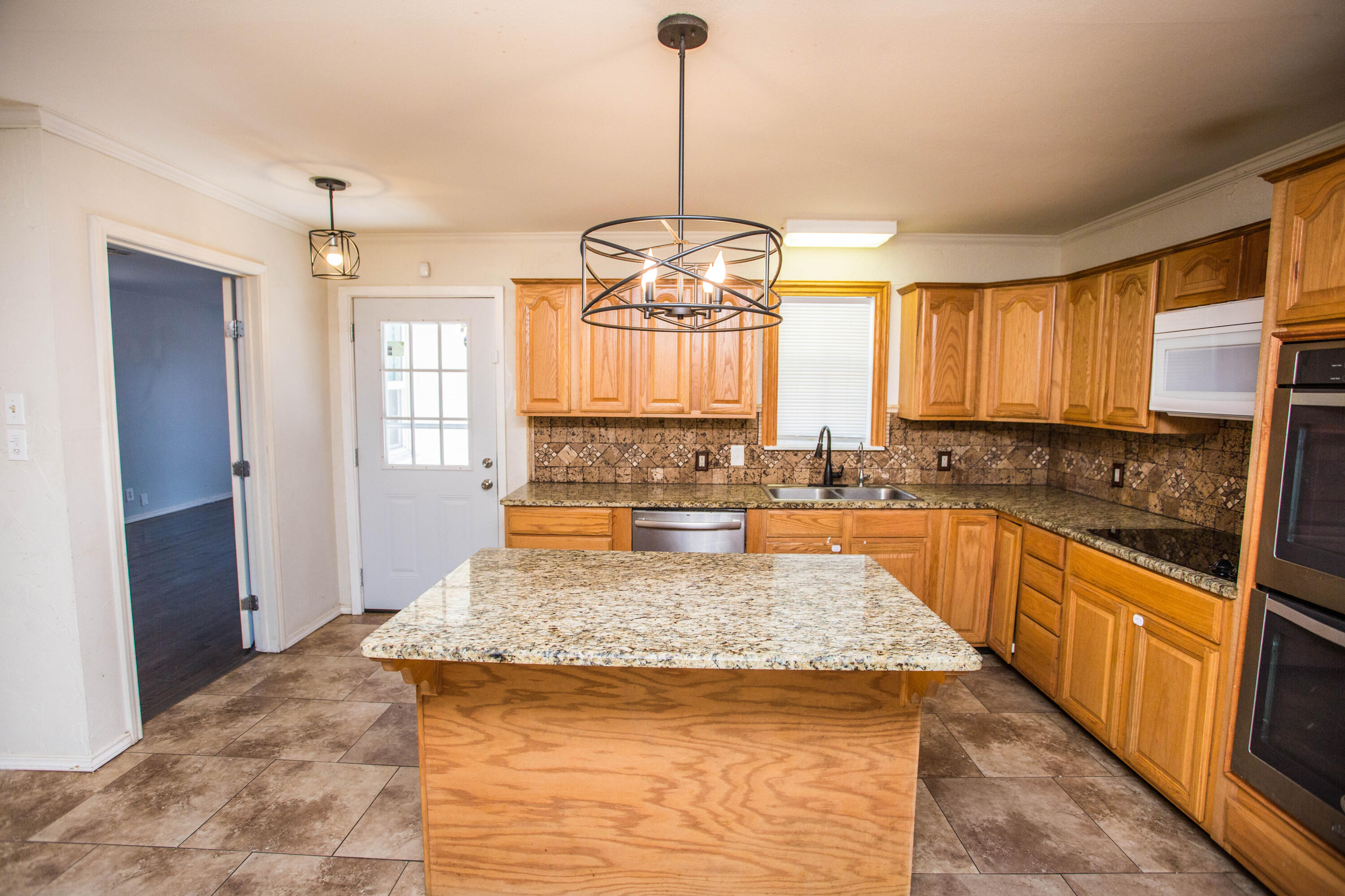 4213 40th Street Lubbock, TX 79413 - Photo 9 of 30 a large kitchen with kitchen island granite countertop a large window and a sink