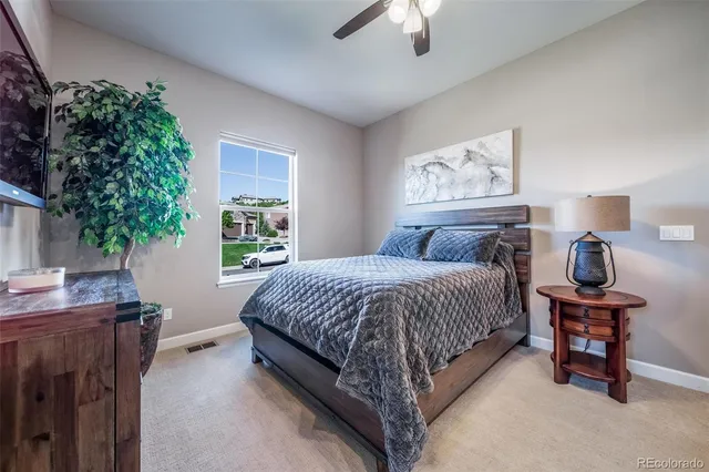 a bedroom with a bed table chair and a potted plant