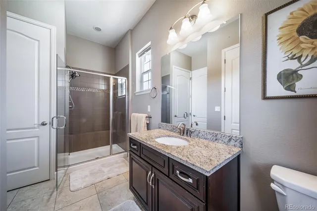 a bathroom with a granite countertop sink a toilet a shower and a mirror