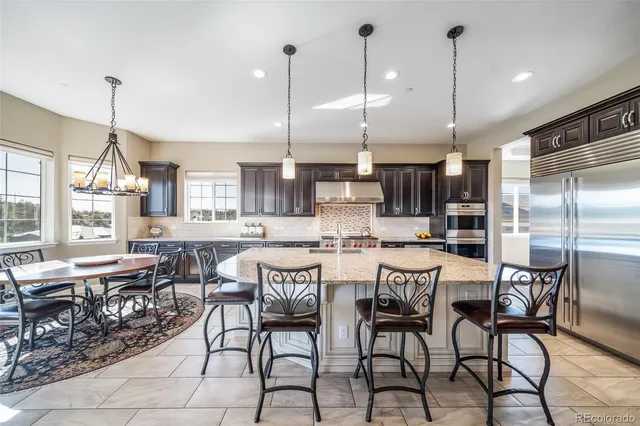a kitchen with stainless steel appliances kitchen island granite countertop a stove a refrigerator a oven a sink with a dining table and chairs