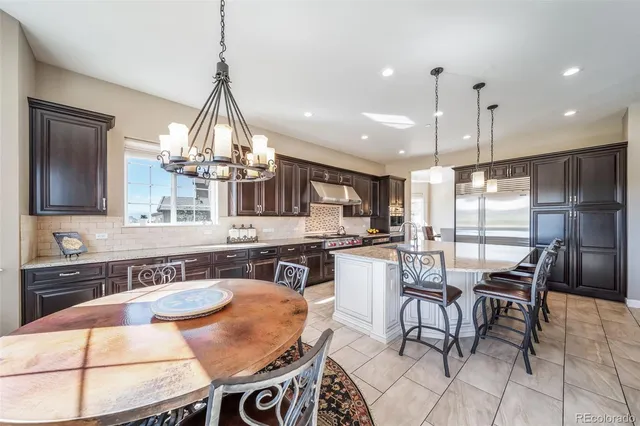 a kitchen with stainless steel appliances granite countertop a sink a stove a table and chairs