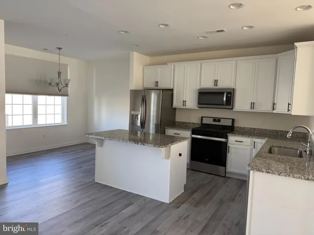 a kitchen with granite countertop a refrigerator stove top oven and sink