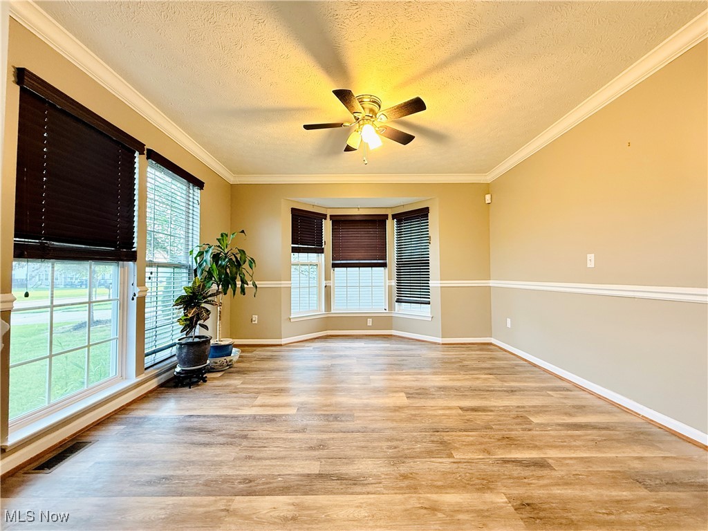 155 Stone Ridge Way Berea, OH 44017 - Photo 6 of 32 Unfurnished room featuring light wood finished floors, healthy amount of natural light, a ceiling fan, a textured ceiling, and crown molding