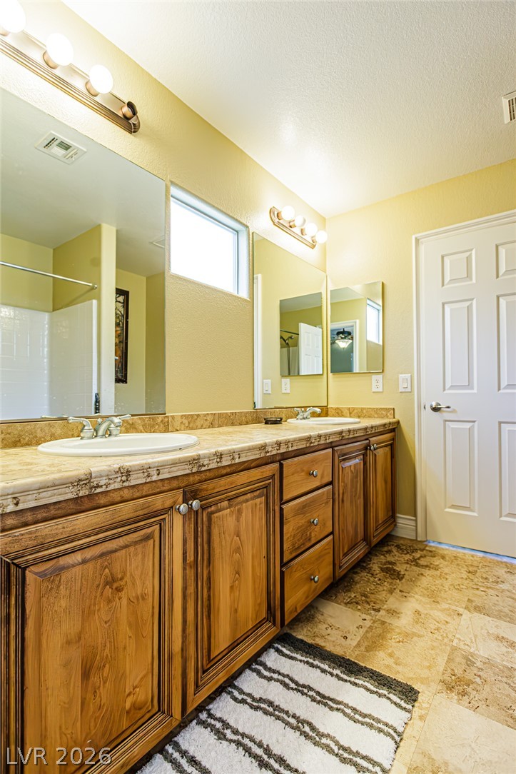 75 Tall Ruff Drive Las Vegas, NV 89148 - Photo 31 of 64 Warm wood cabinetry and tile flooring anchor this functional double vanity bathroom.
