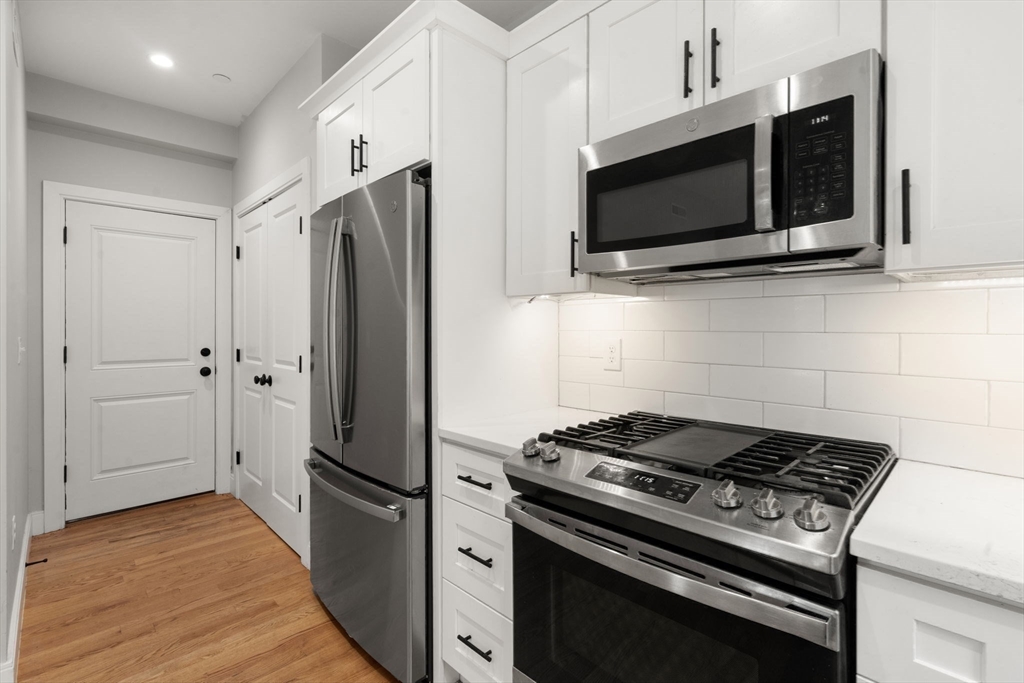 123-125 Centre Street, Unit TH7 Boston, MA 02124 - Photo 16 of 37 a kitchen with stainless steel appliances and wooden cabinets