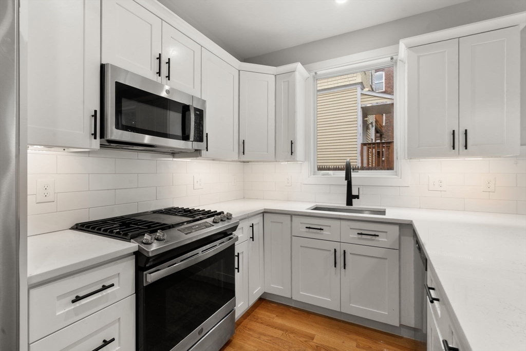 123-125 Centre Street, Unit TH7 Boston, MA 02124 - Photo 17 of 37 a kitchen with white cabinets and stainless steel appliances
