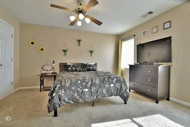 a bedroom with a bed and a flat tv screen on dresser
