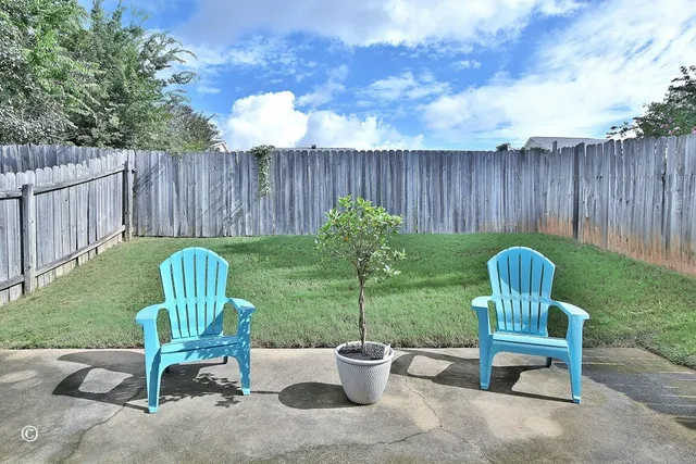 a view of a chair and table in the back yard of the house