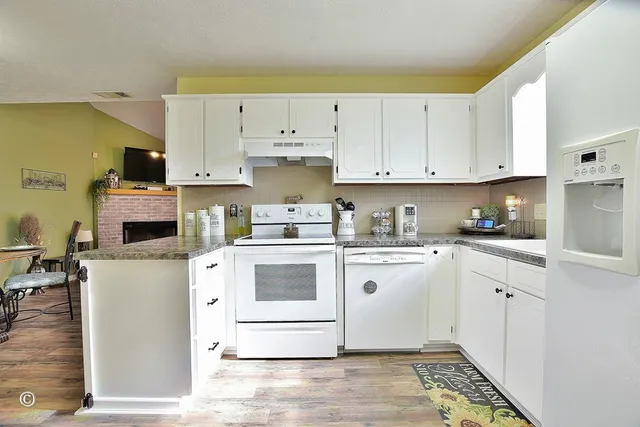 a kitchen with stainless steel appliances granite countertop a stove a sink and white cabinets