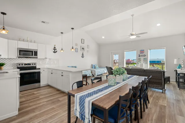 a kitchen with stainless steel appliances a dining table chairs stove and cabinets