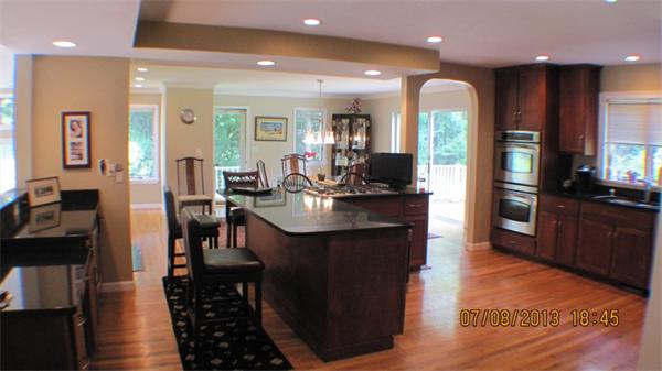a kitchen with stainless steel appliances kitchen island granite countertop a stove top oven a sink dishwasher and a dining table with wooden floor