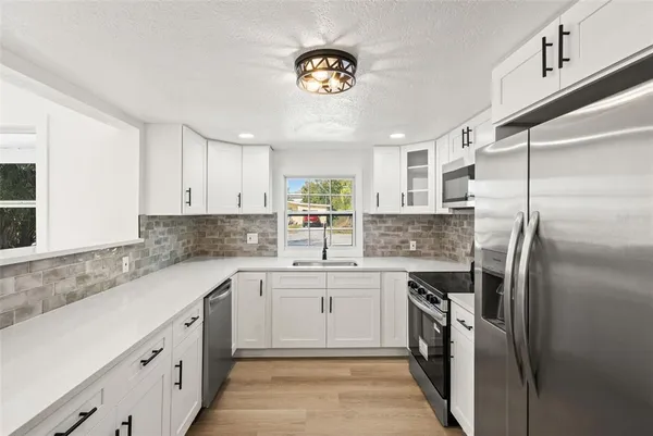 a kitchen with stainless steel appliances a refrigerator a sink a stove a table and chairs