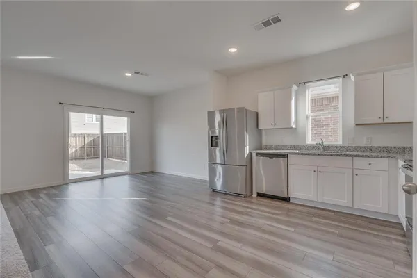 a kitchen with granite countertop a refrigerator sink and cabinets