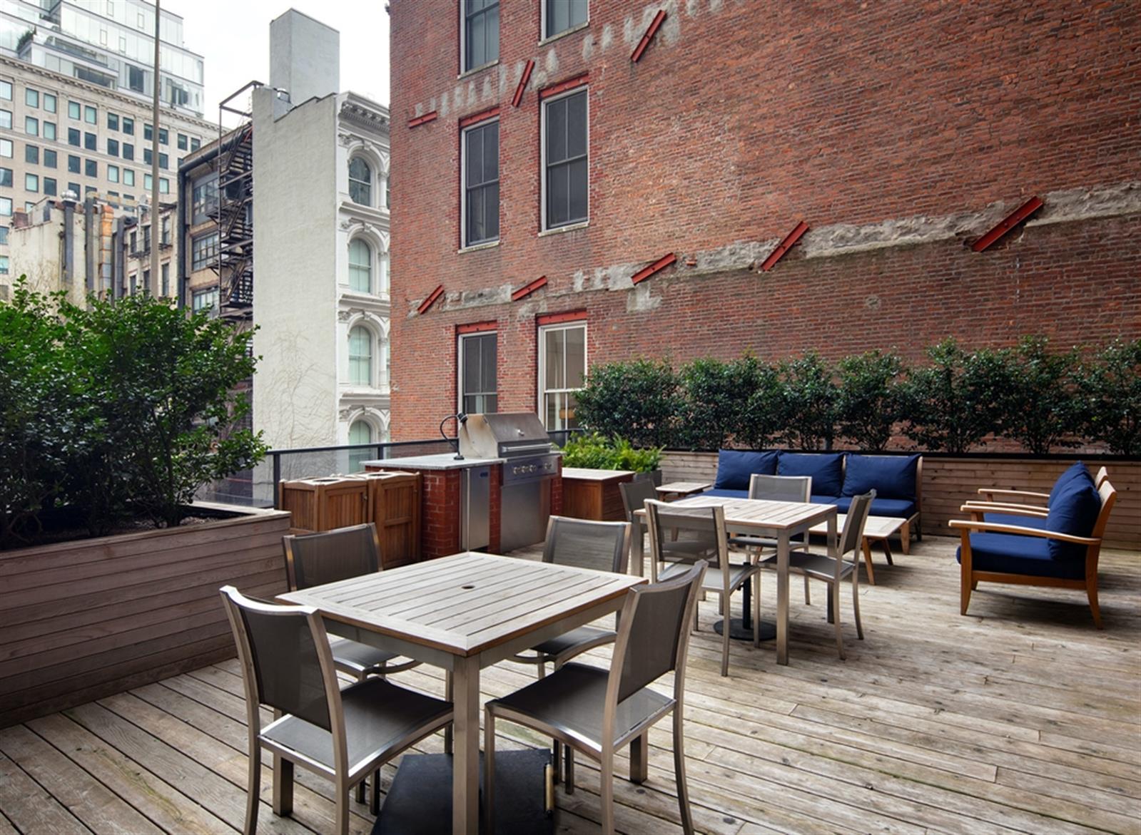a view of a roof deck with table and chairs couches with wooden floor and fence