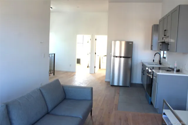 a living room with furniture and a refrigerator