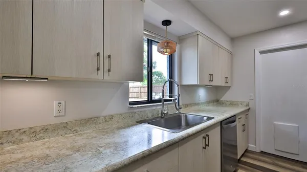 a kitchen that has a sink and cabinets stainless steel appliances